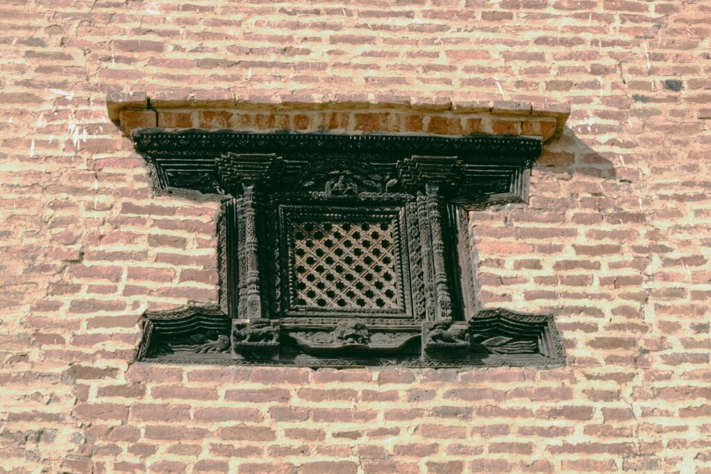 Ornate wooden window set in a brick wall